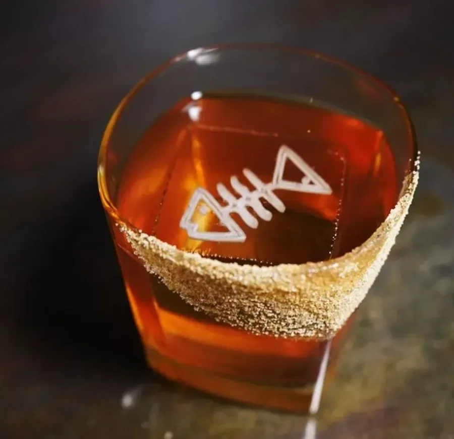 A glass of whiskey with fish artwork from Espiritu.