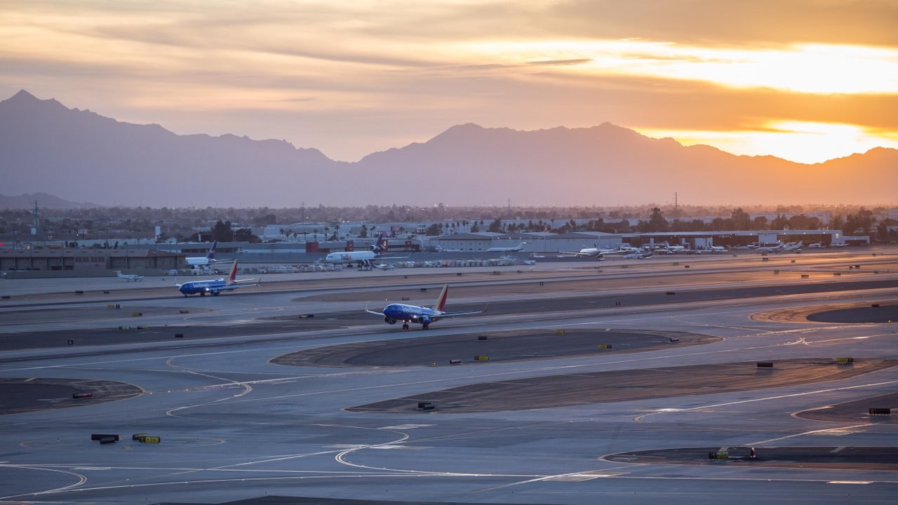 Aircraft on airport runways at sunset with Arizona mountains in the background